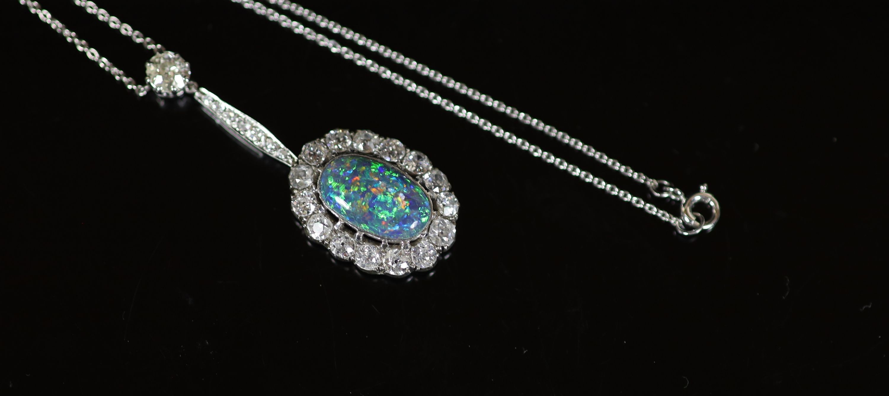 An early 20th century white gold, oval black opal and diamond cluster set drop pendant necklace